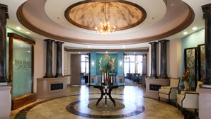 A lobby with a circular marble floor, a central table with a vase, and tall columns.
