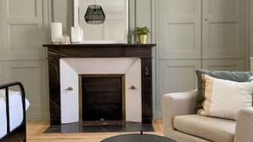 Un salon avec une cheminée, une table ronde noire et un canapé beige.