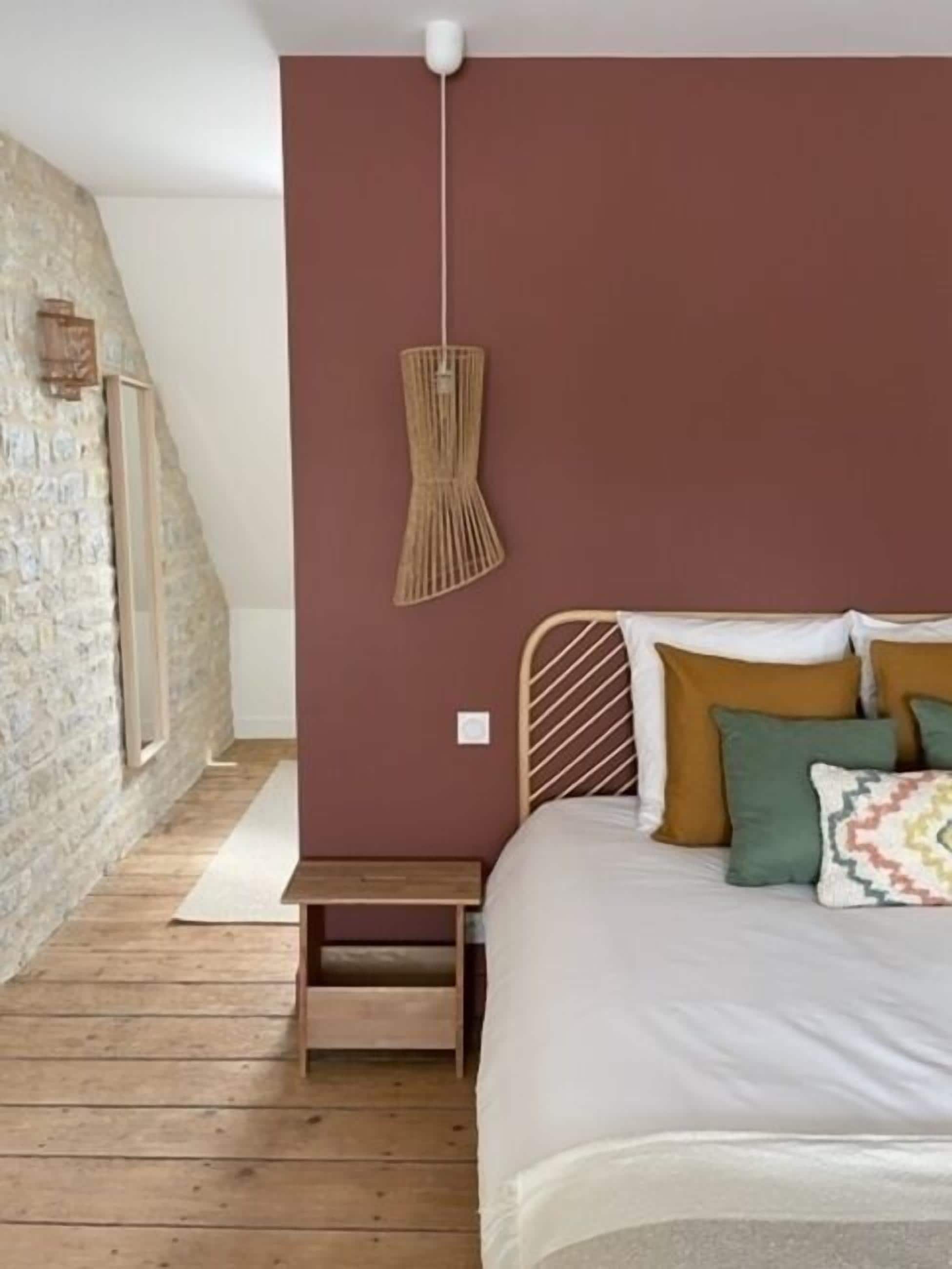 Un dormitorio con una cama, una mesita de noche de madera, una lámpara de pared y una pared de piedra.