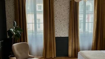 Une chambre d’hôtel avec un lit, une chaise, une petite table et une plante en pot.