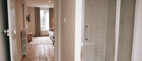 A hallway leading to a bathroom with a glass shower enclosure.