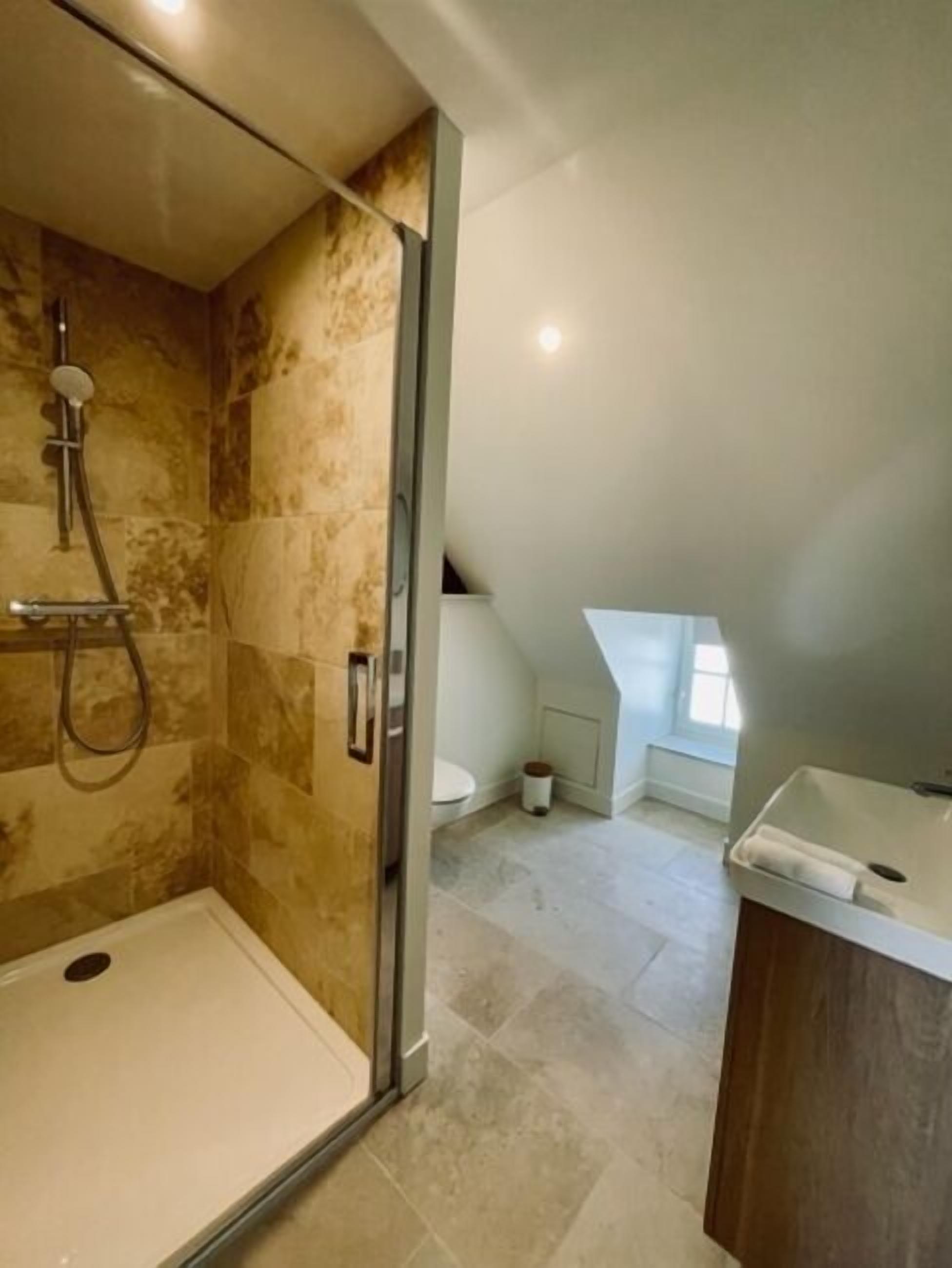 Een moderne badkamer met een douchecabine van glas, een toilet en een wastafel.