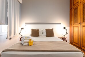 A neatly made bed with a beige blanket, two bedside lamps, and a small table with towels and toiletries. - 5 minutes from Copacabana beach | NSC808 (Rio de Janeiro)