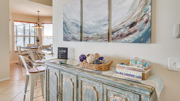 A kitchen with a bar area, a large abstract painting, and a basket of decorative items on the counter. - Cozy Cape Coral Home: 8 Mi to Marina! (Cape Coral)