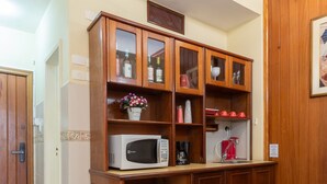 Una cocina compacta con armarios de madera, microondas, refrigerador pequeño y mesa de comedor con sillas.
