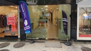 La entrada a ED. KENNEDY 98 con puerta de vidrio, un banderín azul y un letrero que anuncia un descuento del 50%.