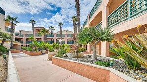 A courtyard with palm trees, planters, and a building with balconies.