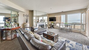 A spacious living room with a leather sofa, a coffee table, and a dining area with a view of the ocean.