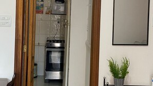 Una cocina con horno, refrigerador y una planta en maceta sobre una estantería.