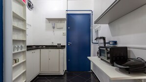 A compact kitchen with white cabinets, a blue door, a microwave, and a coffee maker.