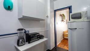 A compact kitchen with a microwave, toaster, and blender on a white countertop.