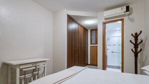 A bedroom with a bed, a desk, and a wardrobe.