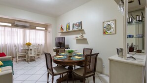 A dining area with a round table, chairs, and a TV in the background.
