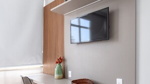 A modern kitchen with a built-in stove, a flat-screen TV mounted on the wall, and a wooden panel accent. - Comfort in Copacabana | 150m from the beach | NSC1203 (Rio de Janeiro)
