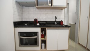 Una cocina compacta con microondas, horno y lavamanos.