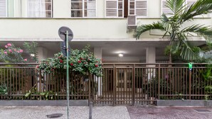 Una entrada protegida con cerramiento metálico, una antena parabólica y una maceta con flores rojas.