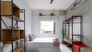 Un dormitorio moderno con cama, estanterías empotradas, un escritorio y un armario.