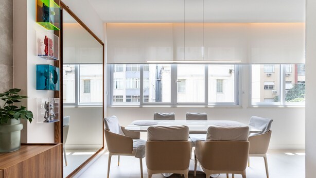 A modern dining area with a round table and chairs, large windows, and artwork on the wall.