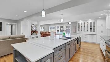 A spacious kitchen with a large island, white cabinetry, and a wooden floor.
