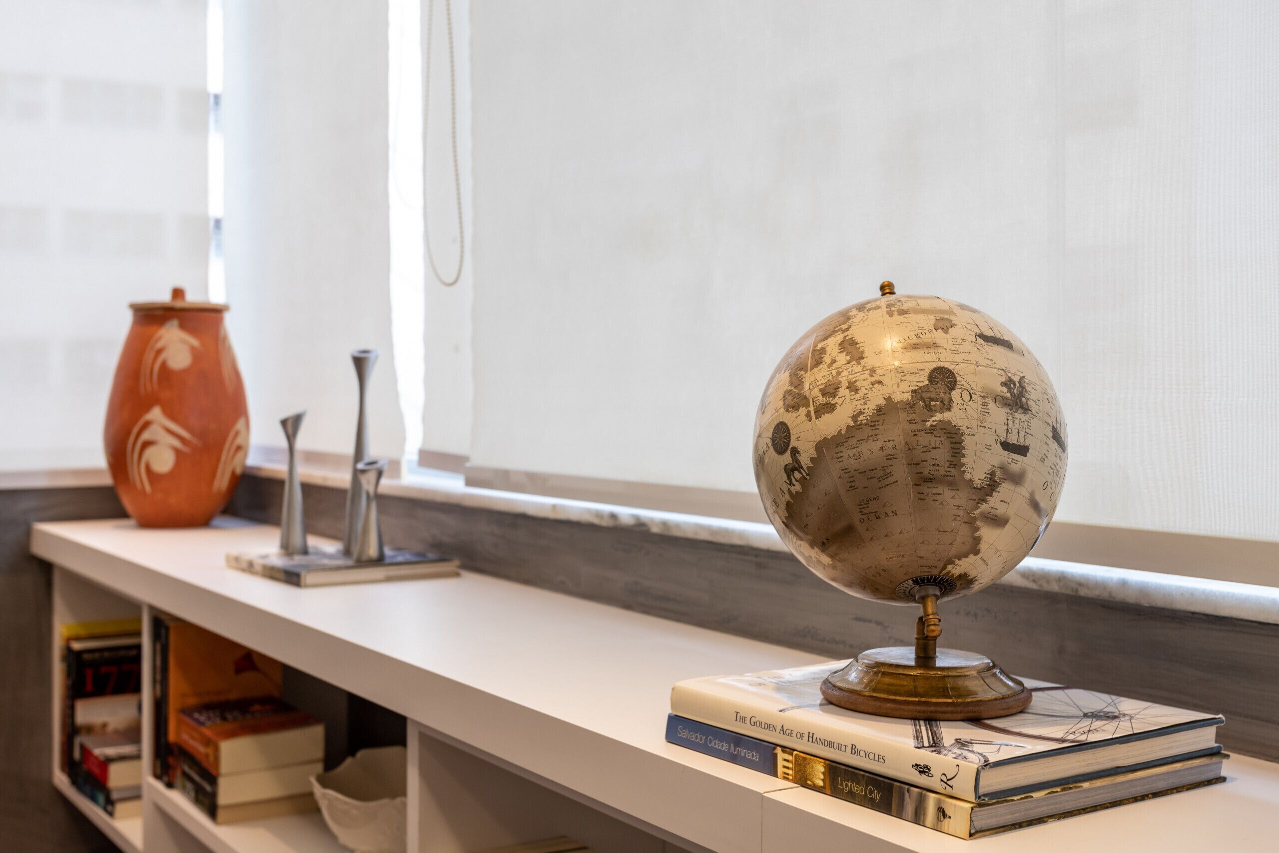 A globe on a stand, a vase, and books on a shelf.