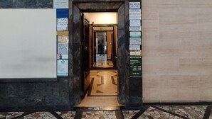 Una entrada con suelo de baldosas, una lámpara arriba y letreros informativos en las paredes.