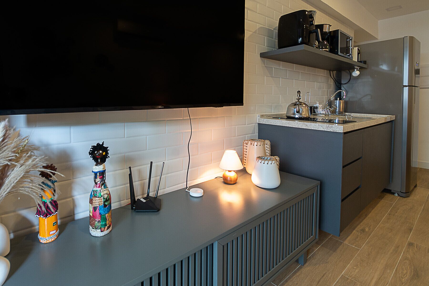 Eine moderne Küche mit integriertem Fernseher, einer Kaffeemaschine und einem Wasserkocher auf der Arbeitsfläche.
