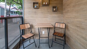 Un petit espace extérieur aménagé avec deux chaises en bois et une table, un mur en bois et un luminaire suspendu.