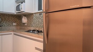 A kitchen with white cabinets, a stainless steel refrigerator, a microwave, and a tiled backsplash. - 3 minutes from Copacabana beach | STC303 (Rio de Janeiro)
