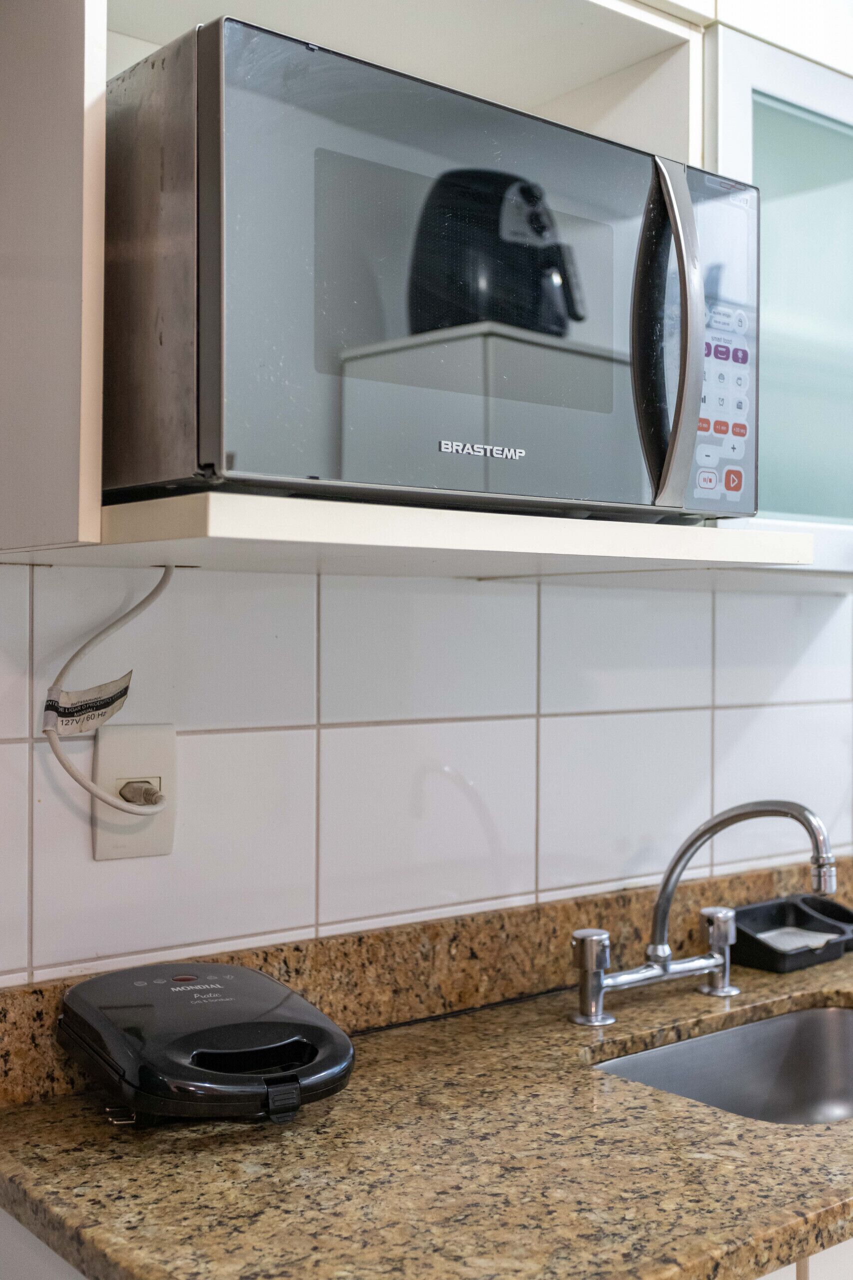 A kitchen with a microwave, a coffee maker, and a vacuum cleaner.