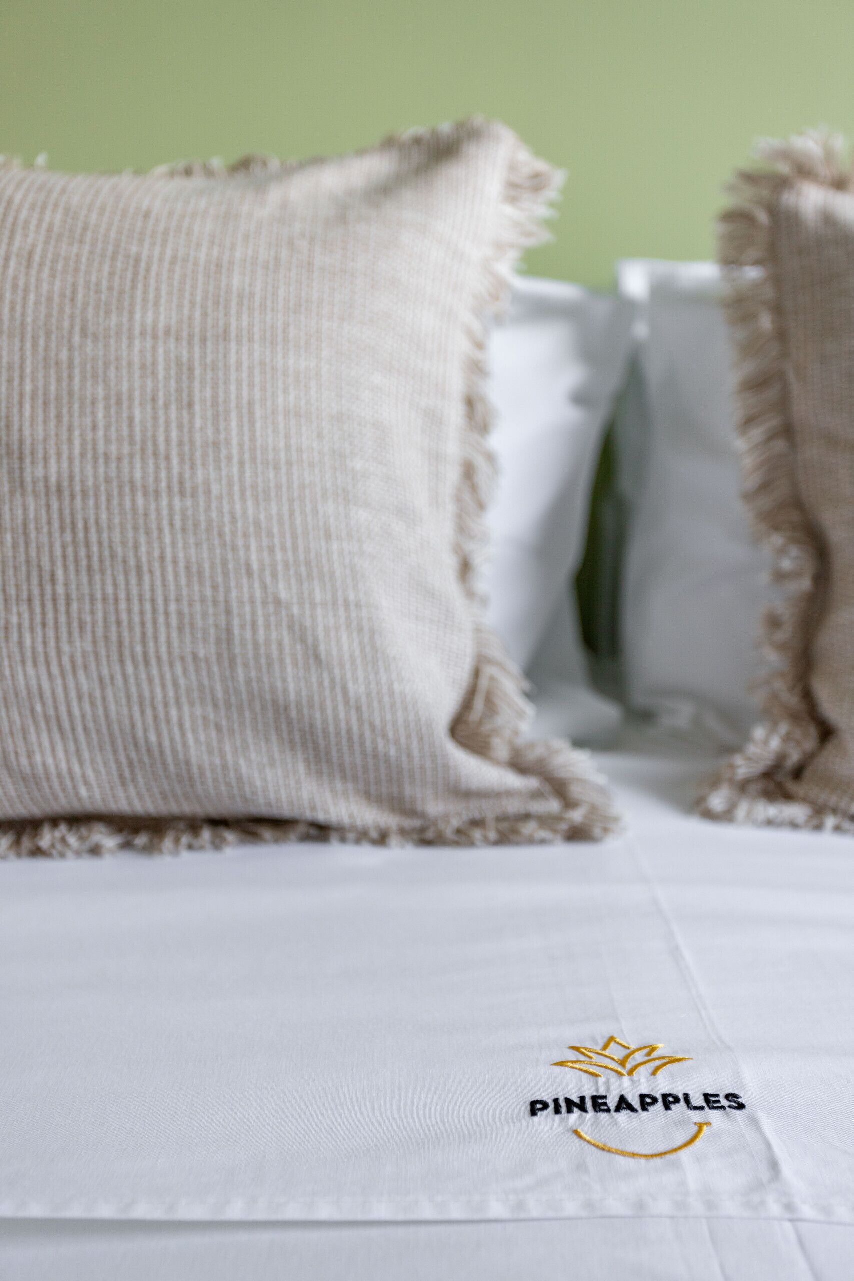 A bed with white bedding and a pillow with frayed edges.