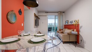 A modern living room with a dining area, a sofa, and a balcony with a city view. - Beauty at Recreio | For 5 peopple | SA201 (Rio de Janeiro)