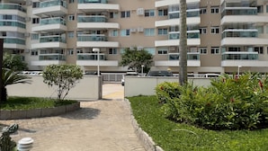 A multi-story residential building with balconies, a palm tree, and a paved pathway. - Beauty at Recreio | For 5 peopple | SA201 (Rio de Janeiro)