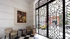 Un hall d’entrée avec un sol à carreaux, deux canapés, une petite table et un grand tableau abstrait accroché au mur.