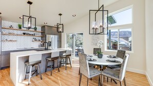 A modern kitchen with a central island, bar stools, and pendant lighting. - Hot Tub & Panoramic Mtn Views: Pine Retreat! (Pine)