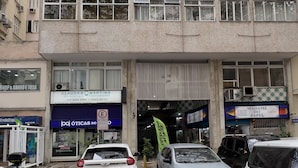 A multi-story building with several shops on the ground floor, including a bank and a store named 'Madame do Papel'.