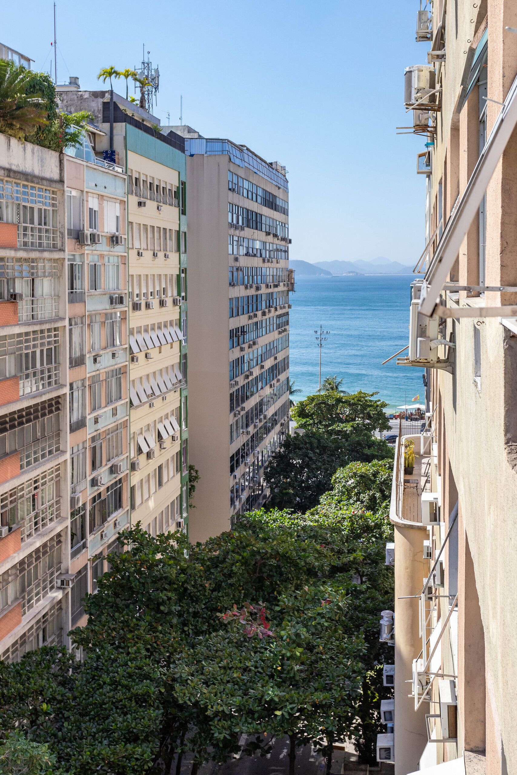 A high-rise building with multiple balconies overlooking a coastal area.