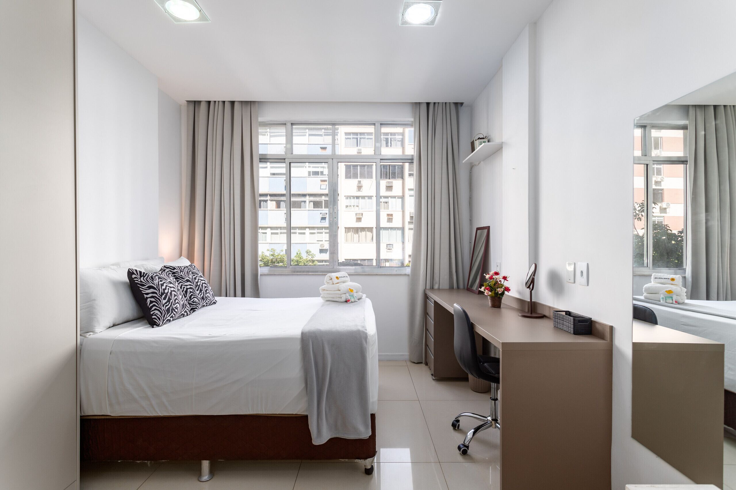 Ein modernes Hotelzimmer mit Bett, Schreibtisch und großen Fenstern.