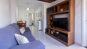 A living room with a blue sofa, wooden entertainment unit, and a TV.