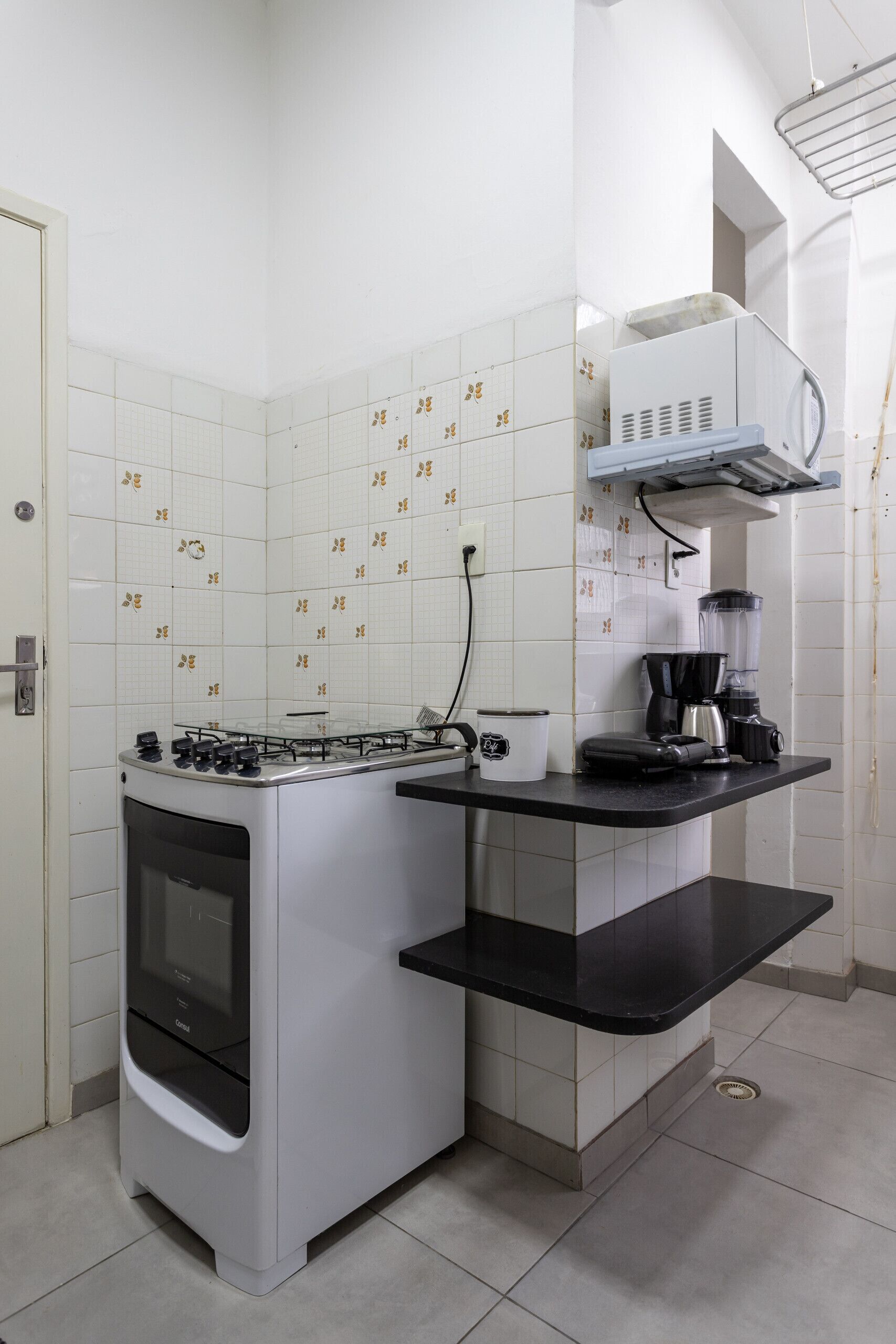 Una cocina con estufa, cafetera y licuadora sobre una encimera negra.