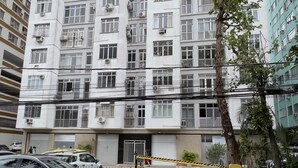 A multi-story residential building with balconies, a gated entrance, and parked cars.