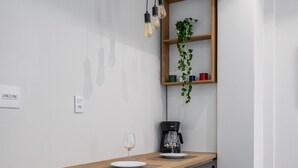 A modern dining area with a wooden table, black chairs, a coffee machine, and hanging light fixtures. - Near the underground and 20 minutes from Maracanã | CV410 (Rio de Janeiro)