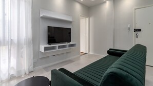 A modern living room with a flat-screen TV mounted on a white wall, a green sofa, and a small table. - Near the underground and 20 minutes from Maracanã | CV410 (Rio de Janeiro)