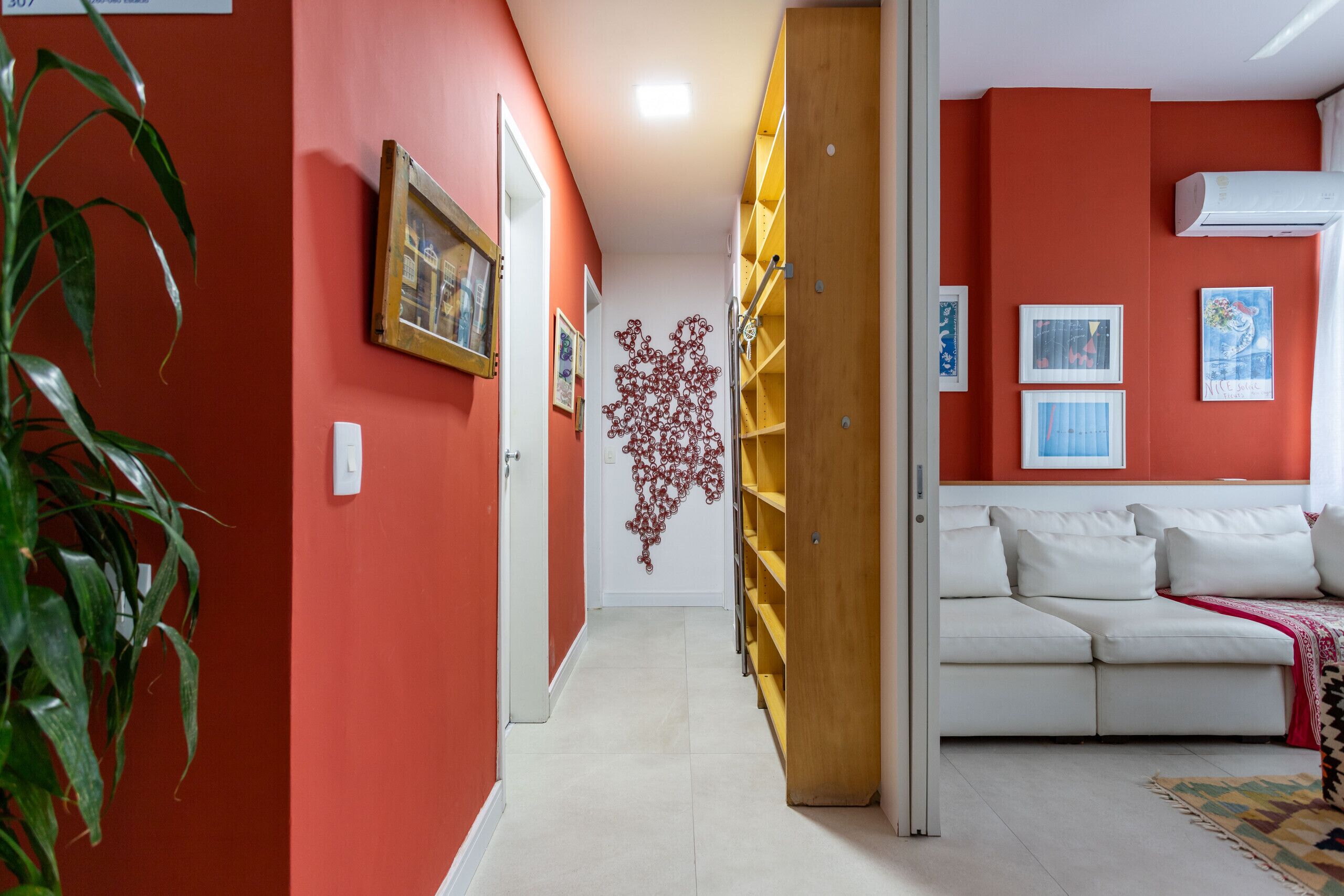 Ein Flur mit roter Wand, einem weißen Sofa und einer Holzhochentruhe.