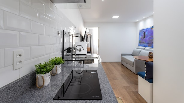 A modern kitchen with white tiles, a black induction cooktop, and potted plants. - Friendly in Copa | Ideal for couples | NSC1209 (Rio de Janeiro)