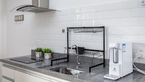 A kitchen with a stainless steel sink, a black drying rack, a water dispenser, and a sign that says "HOME". - Friendly in Copa | Ideal for couples | NSC1209 (Rio de Janeiro)