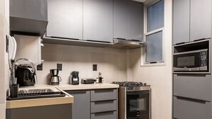 A modern kitchen with grey cabinets, a built-in oven, a microwave, and a coffee maker. - 5 minutes from Leblon Beach | AP302 (Rio de Janeiro)