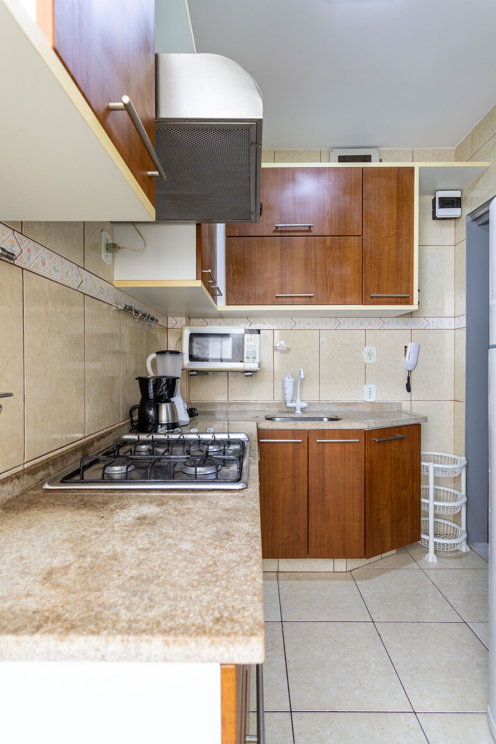 Cocina compacta con estufa a gas, microondas y armarios de madera.