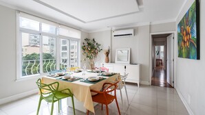 A bright dining area with a table set for four, a potted plant, and a view of buildings outside. - For families, 3 minutes from Copacabana beach | SL501 (Rio de Janeiro)