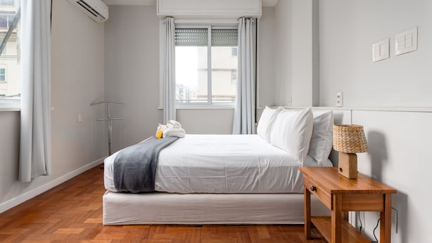 A modern hotel room with a bed, bedside table, and a window with curtains. - For families, 3 minutes from Copacabana beach | SL501 (Rio de Janeiro)