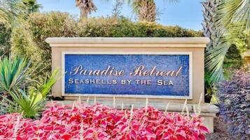 A sign for Paradise Retreat with the text 'SEASHELLS BY THE SEA'.